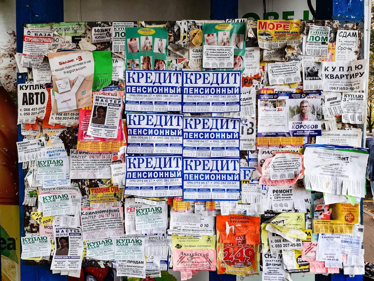A bunch of paper ads on a wall on the streets.
